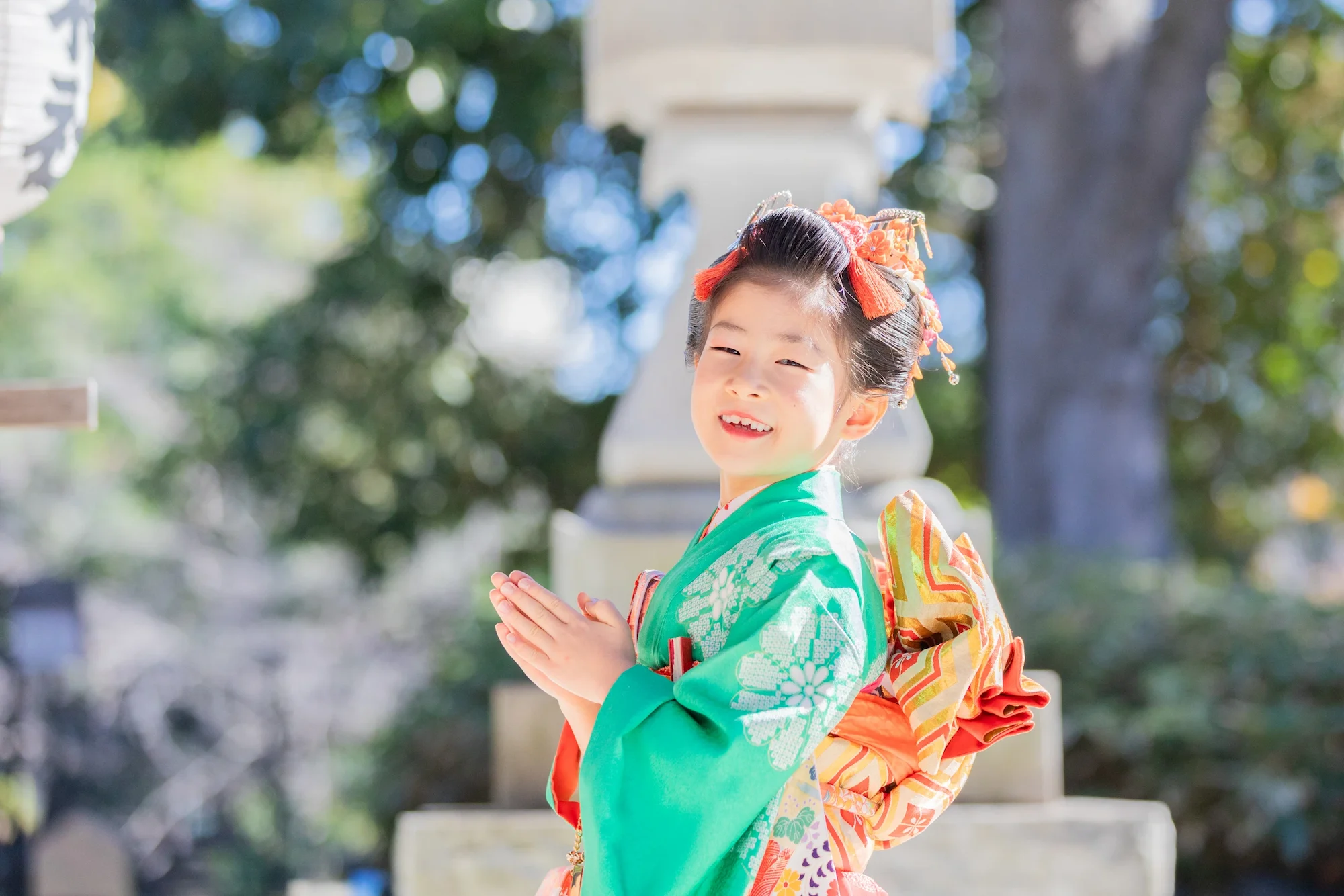 神社で手を合わせる着物を着た七五三の女の子