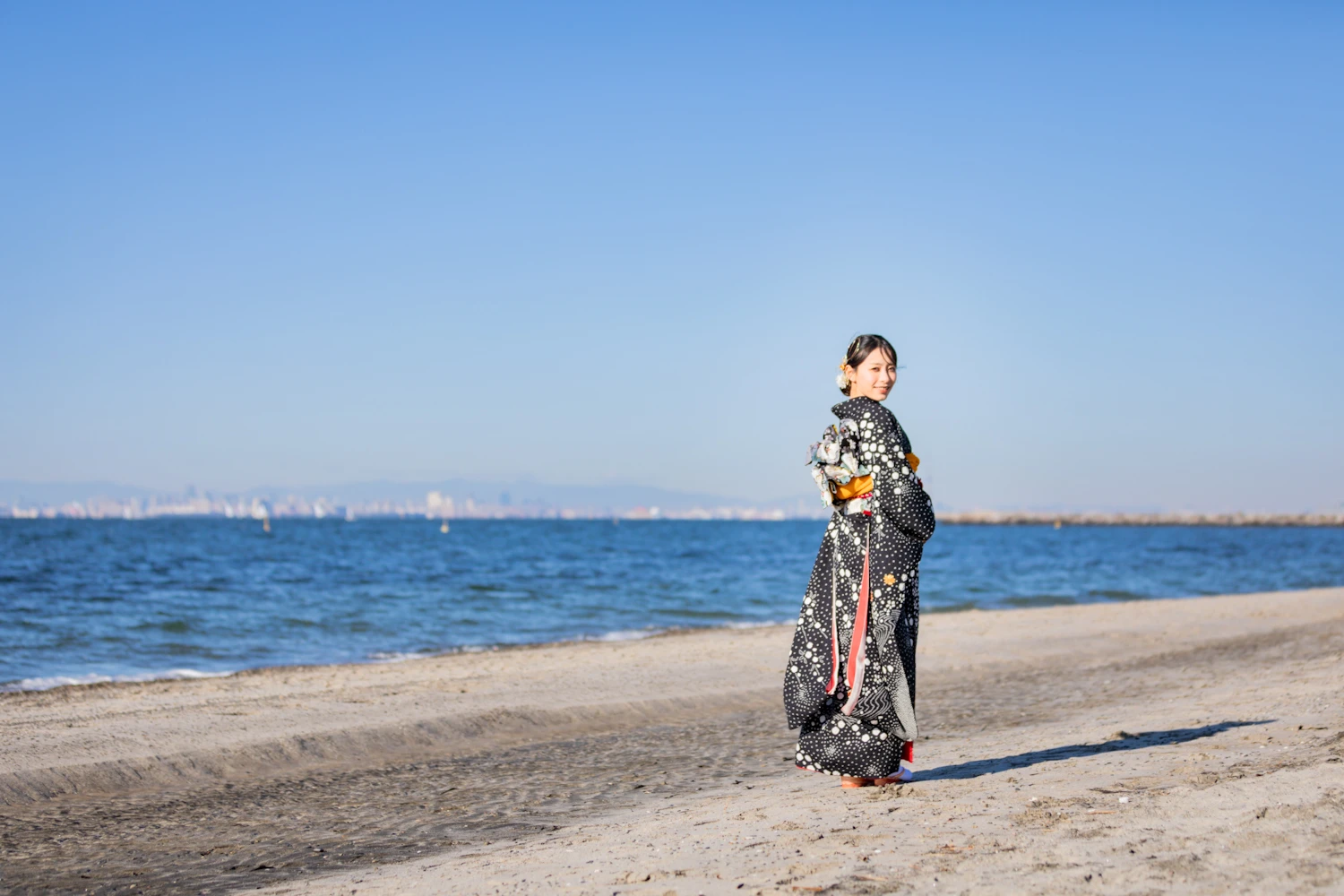 砂浜でご成人の出張撮影をしている着物姿の女性