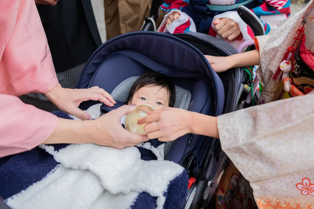 お宮参りの出張撮影でベビーカーに乗ってミルクを飲む赤ちゃん
