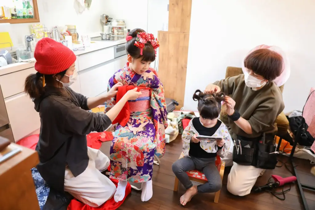 七五三の着物を着付けてもらっている女の子と、ヘアセットをしてもらっている女の子