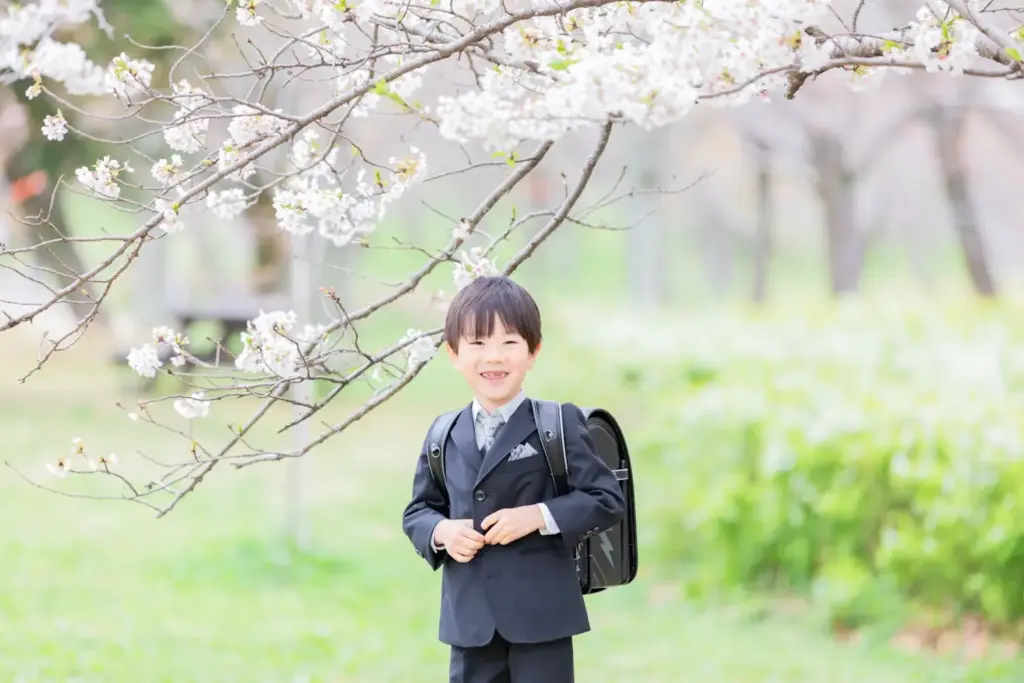 桜の木の下でスーツを着てランドセルを背負っている男の子