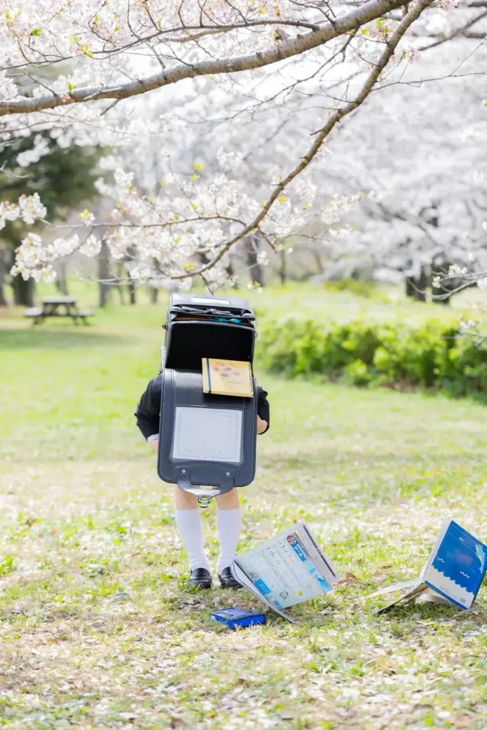 桜の木の下でランドセルから中身が飛び出してしまった男の子