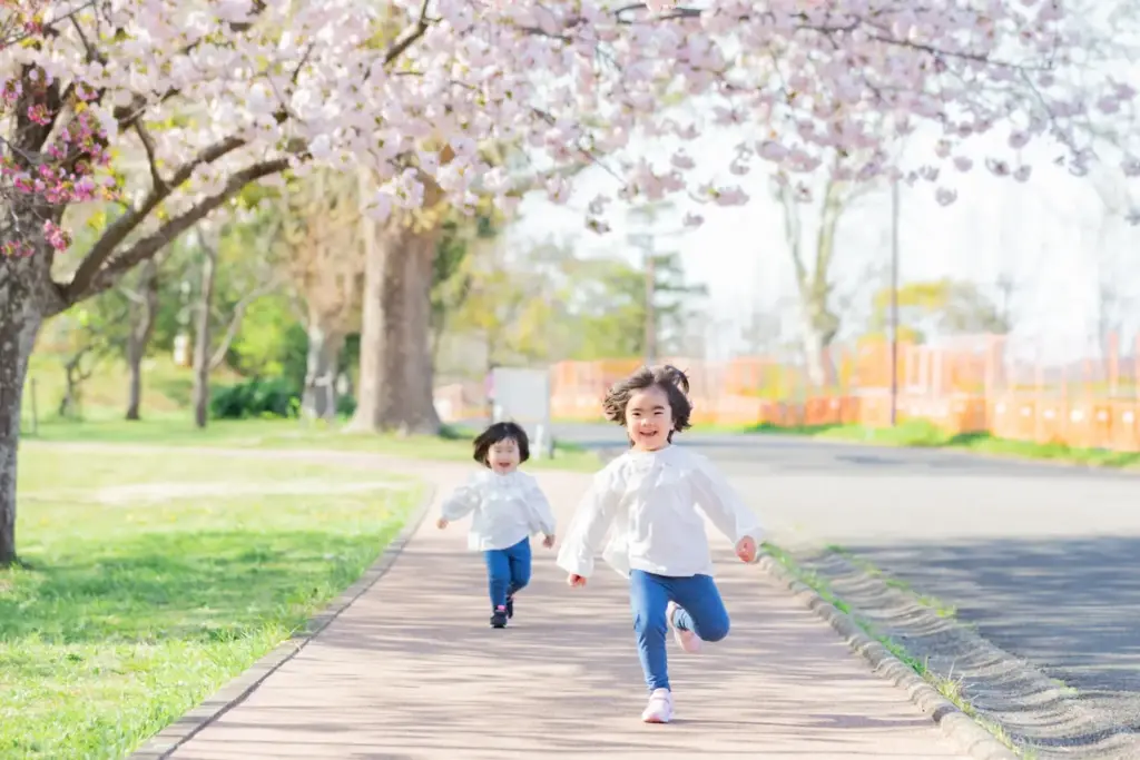 青葉の森で八重桜の下を走る姉妹