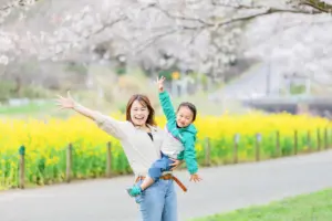 桜と菜の花をバックに楽しそうに微笑む親子の写真。花島公園での桜撮影会。