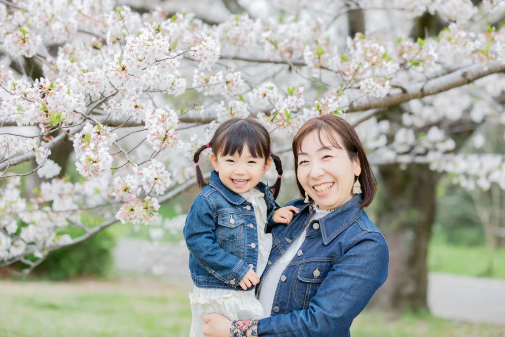 桜の前でにっこり微笑む母娘
