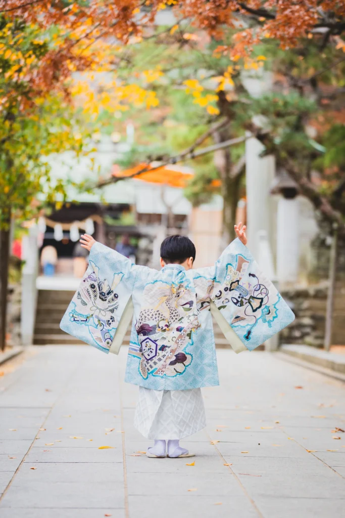 神社の紅葉と水色の羽織袴が綺麗にマッチした七五三写真